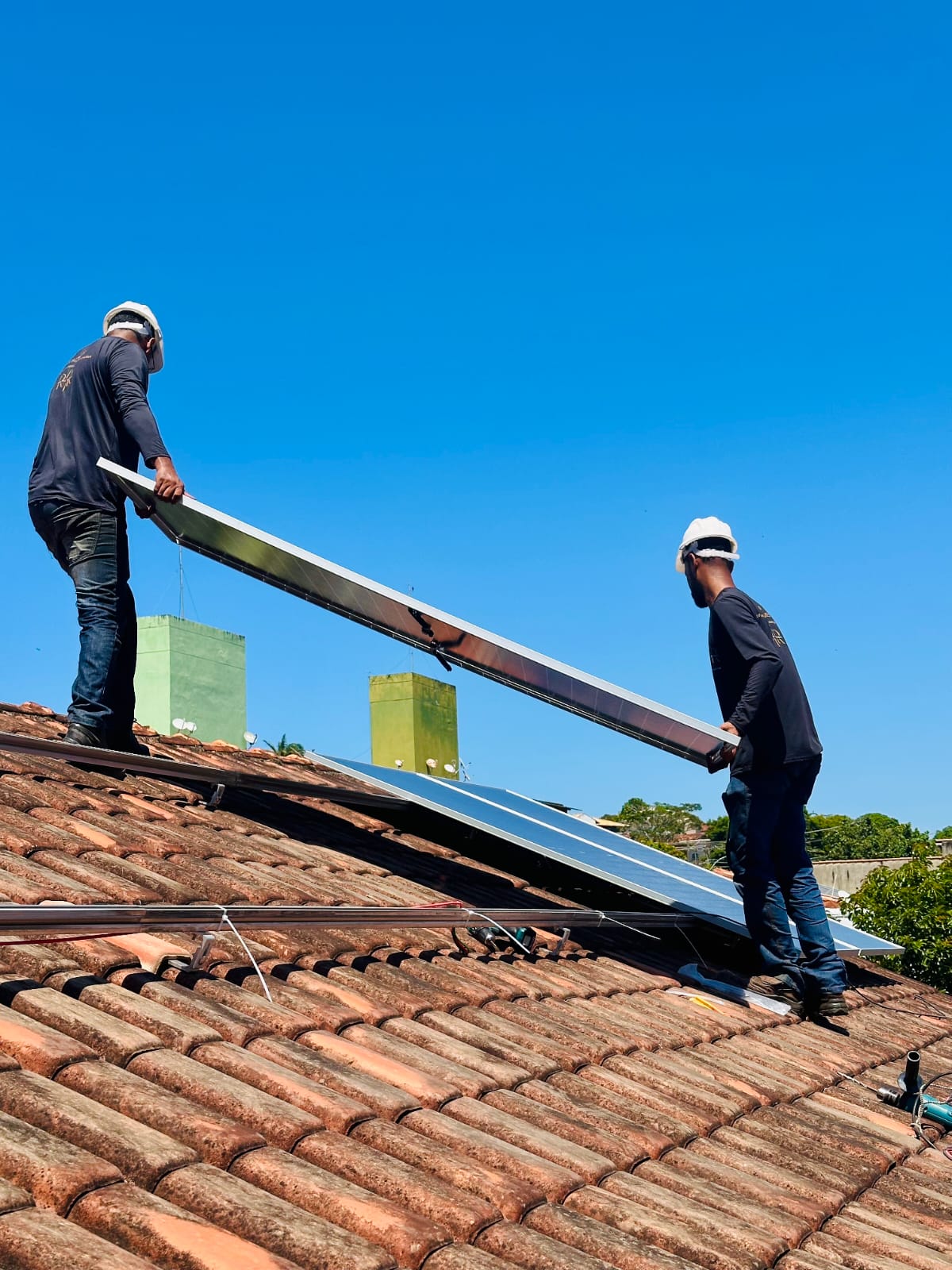 Dois técnicos da RR Solares no telhado posicionando um painel fotovoltaico