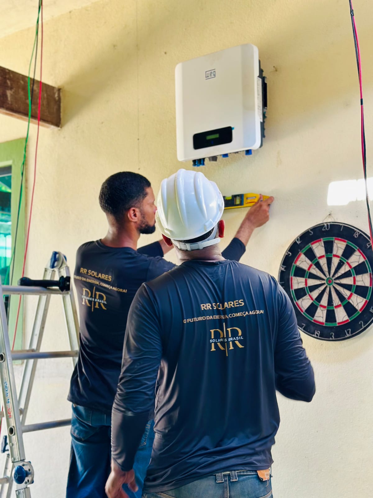 Instalação e nivelamento do inversor WEG na parede por dois técnicos da RR Solares